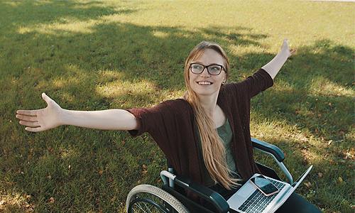 a student sitting in a wheel chair with her arms outstretched.